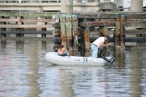 couple in life raft. He's trying to untangle fishing line.