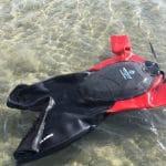 Airtime Waterline wet suit with flotation device in the chest (black with red sleeves) swimming in the ocean