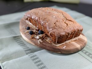 lemon-tea bread with lemon icing and blueberries surrounding the tea bread on a cutting board, gluten, dairy free a recipe from the book - Only Safe Desserts by Robin G Coles