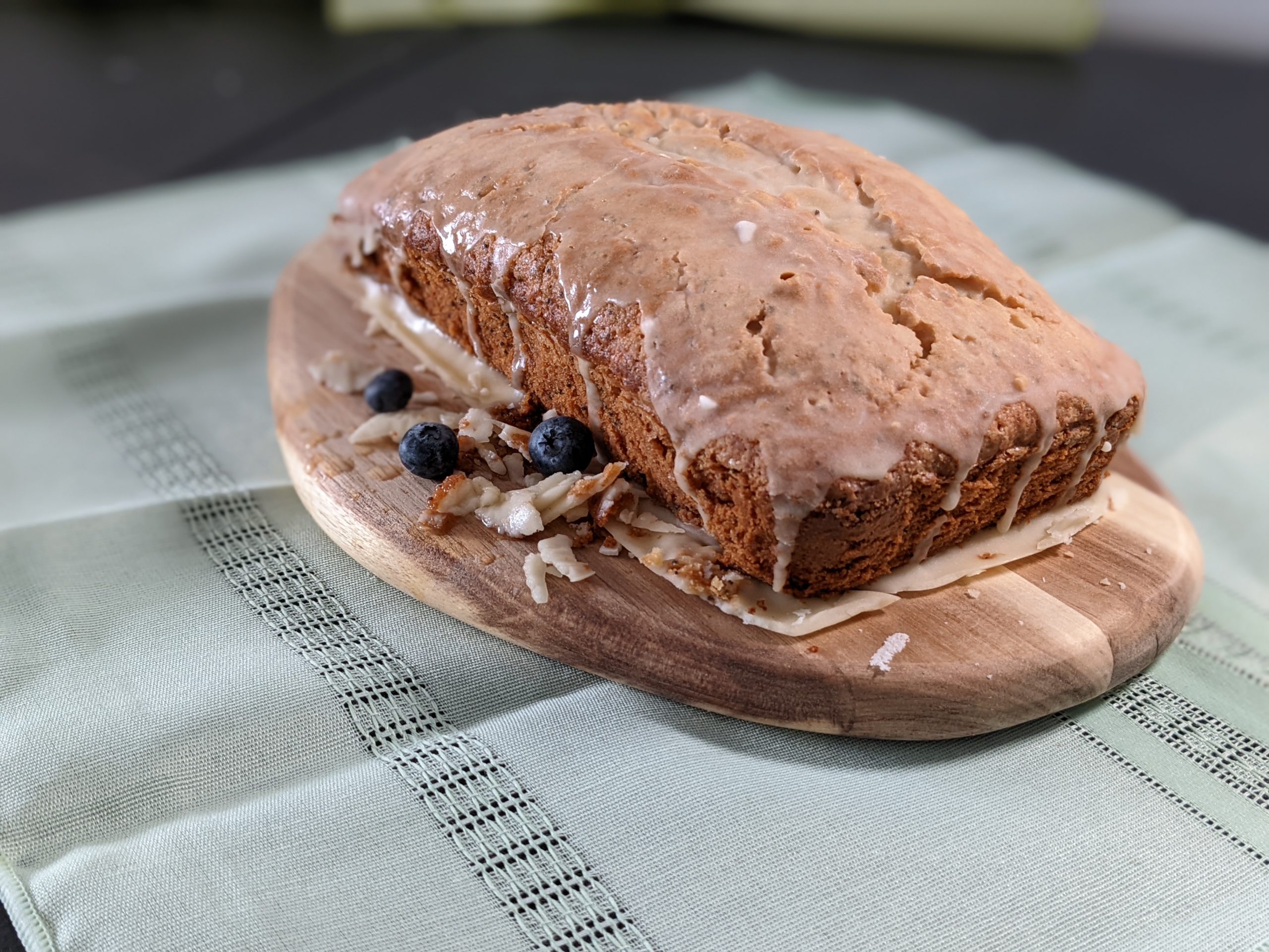 lemon-tea bread with lemon icing and blueberries surrounding the tea bread on a cutting board, gluten, dairy free a recipe from the book - Only Safe Desserts by Robin G Coles